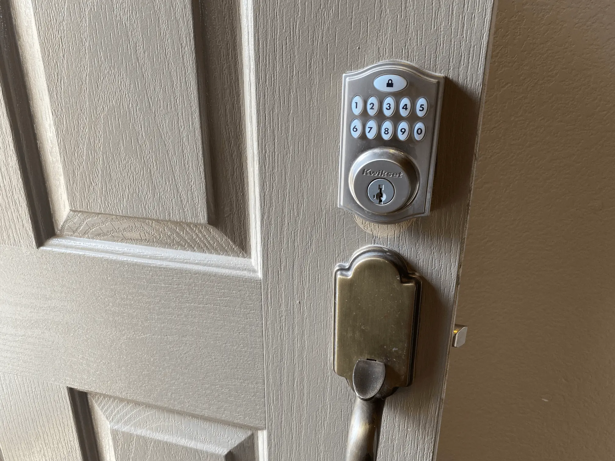 Close-up of a brass-colored door handle and a deadbolt lock on a light-colored door