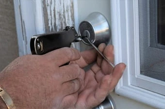 A man is opening the lock of door using tools